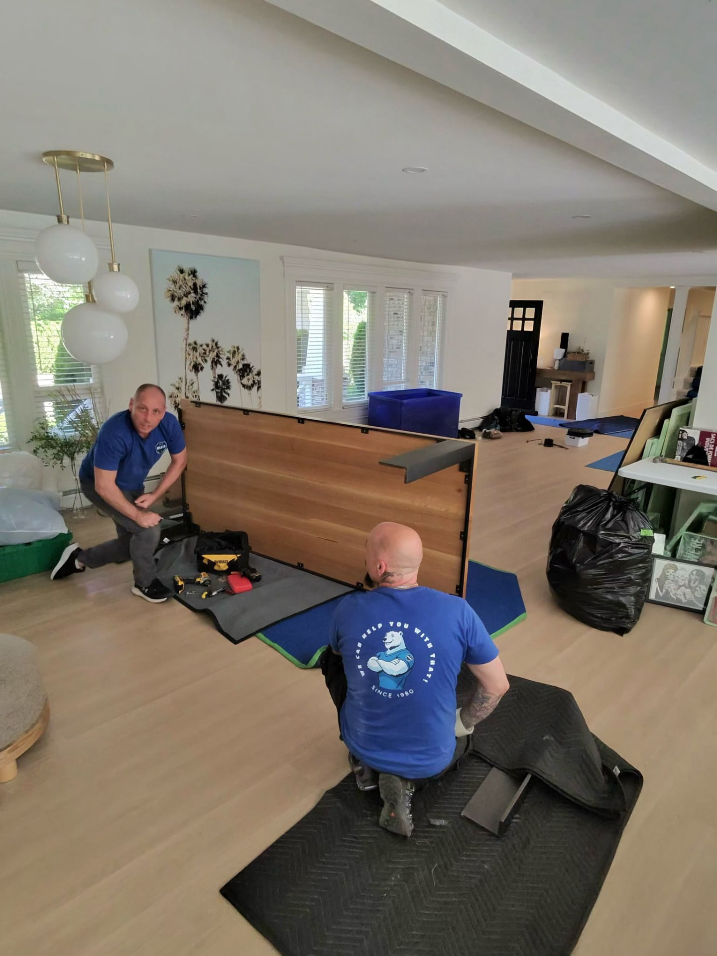 Ellis movers carrying a wrapped sofa through a Whistler timber-frame chalet
